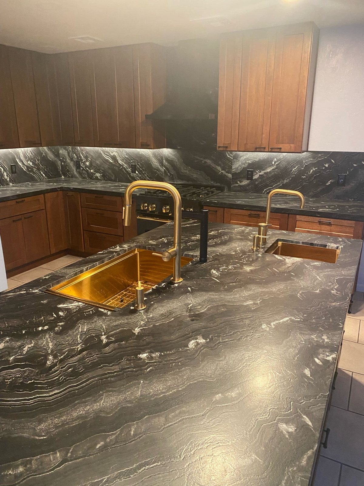 Dark granite countertop with gold sink and faucets closeup