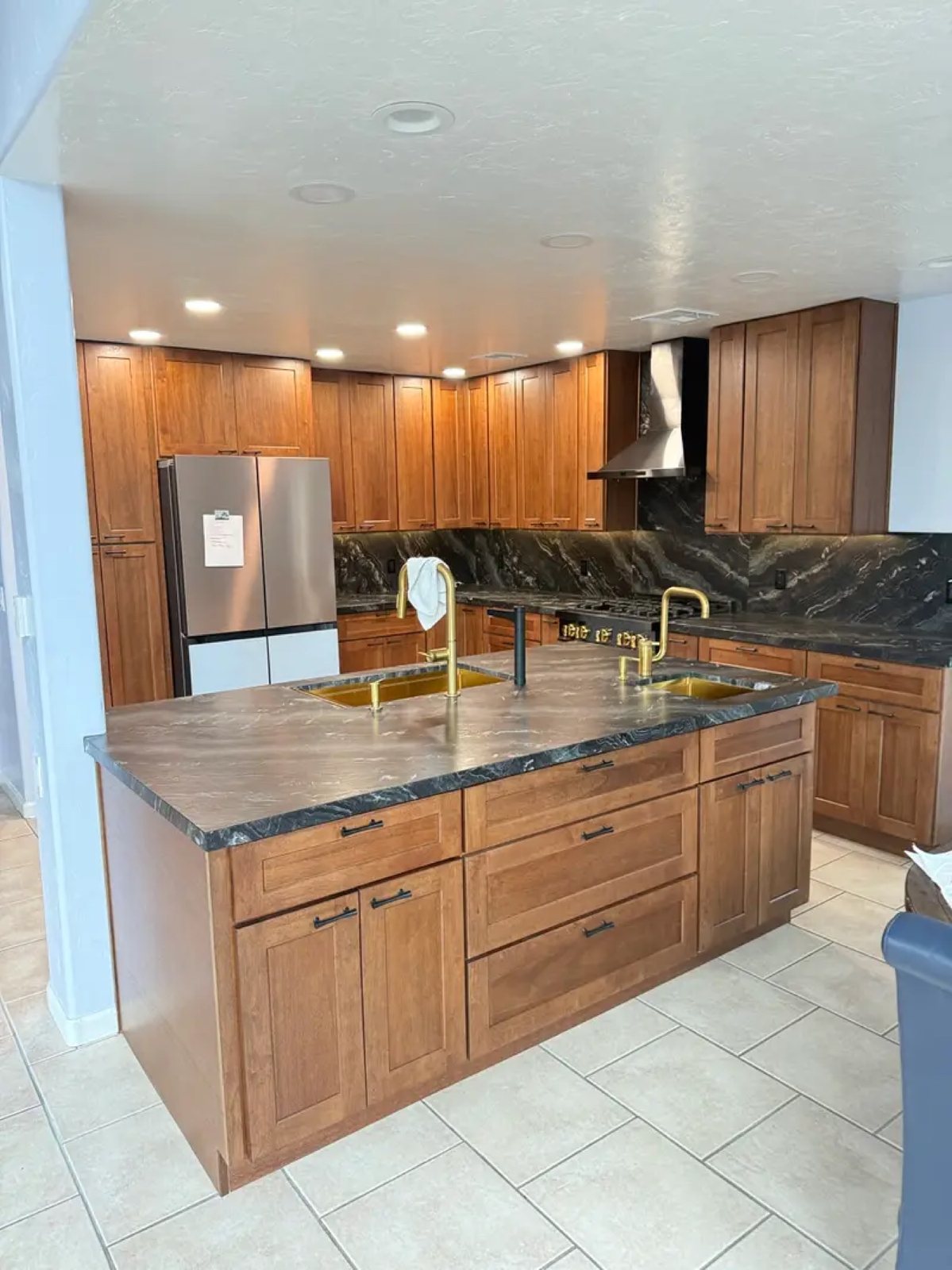 Dark walnut kitchen with black granite countertop and gold sinks