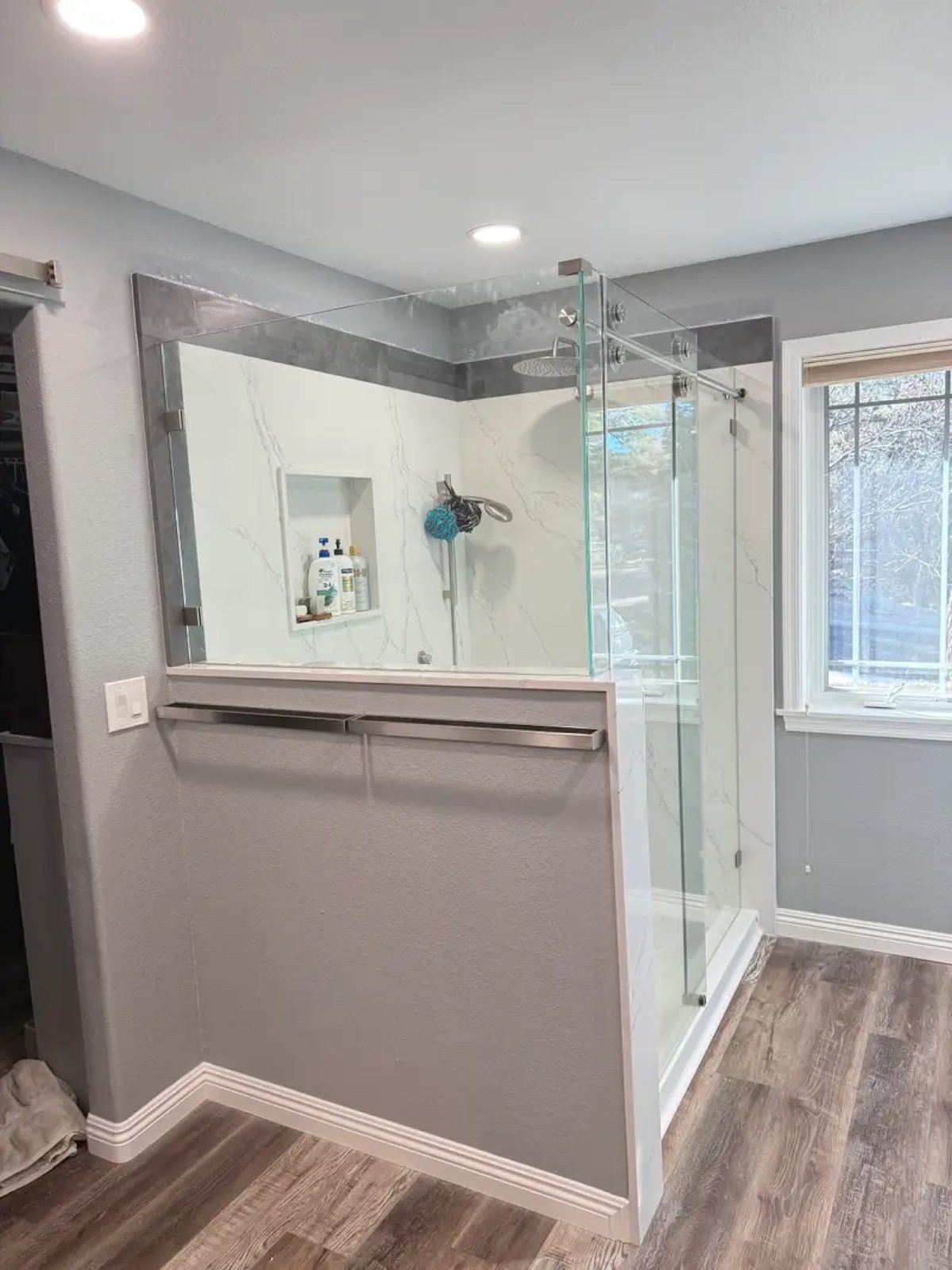 Frameless glass shower with marble panels and gray walls