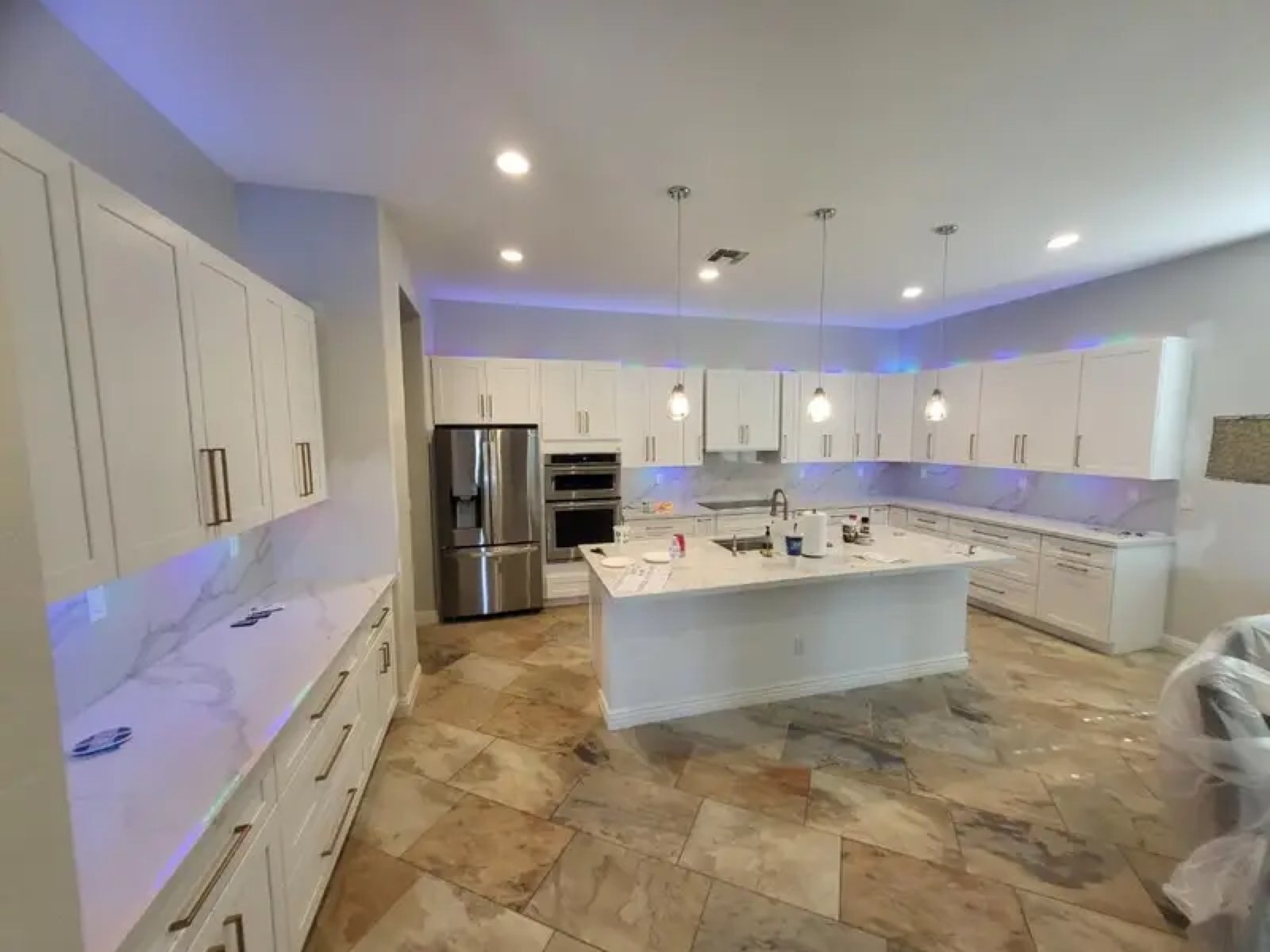 Large white kitchen with marble island and LED pendant lights