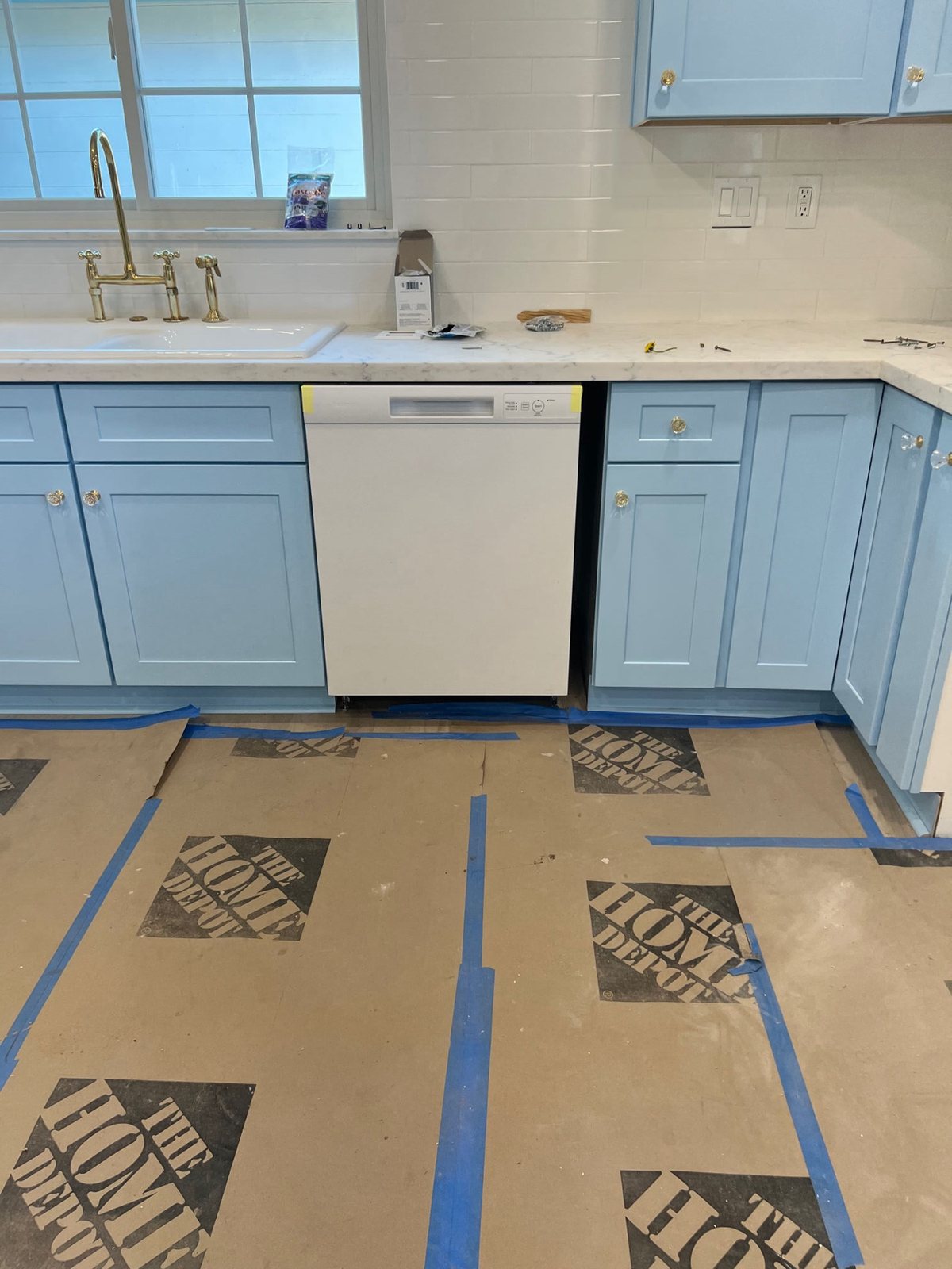 Light blue kitchen cabinet installation with gold hardware