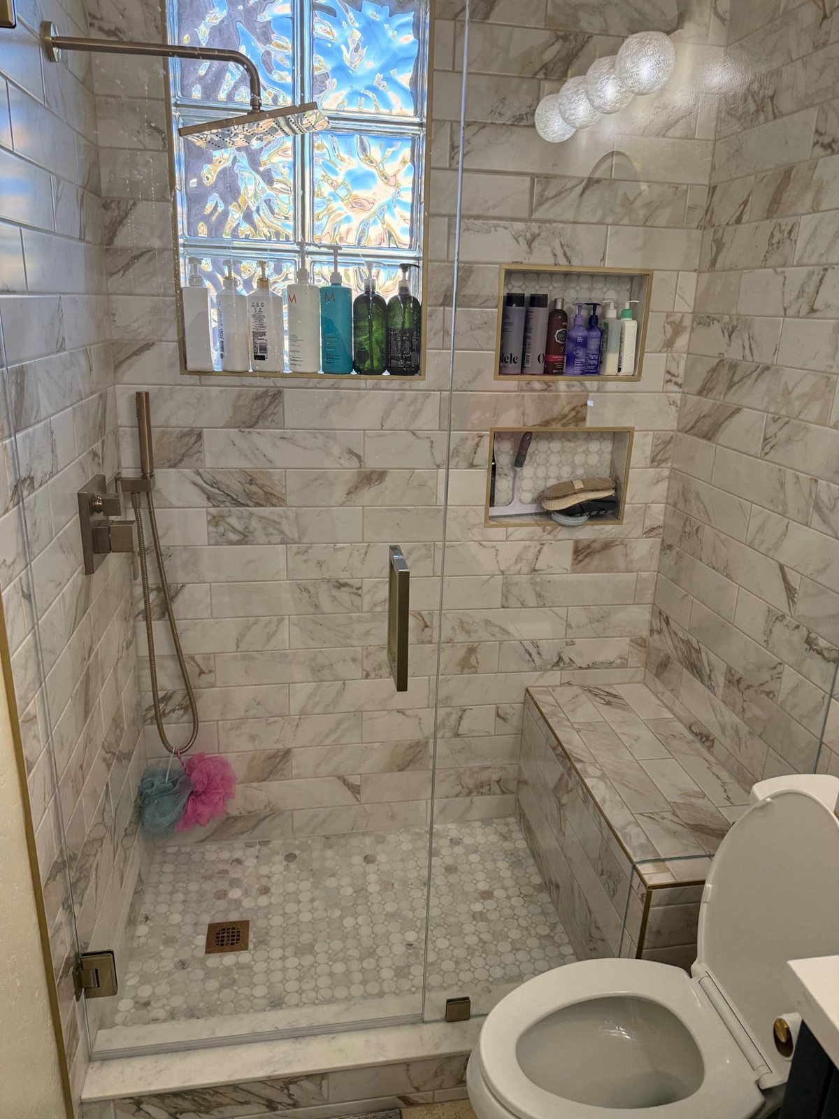 Marble tile shower floor to ceiling with gold fixtures