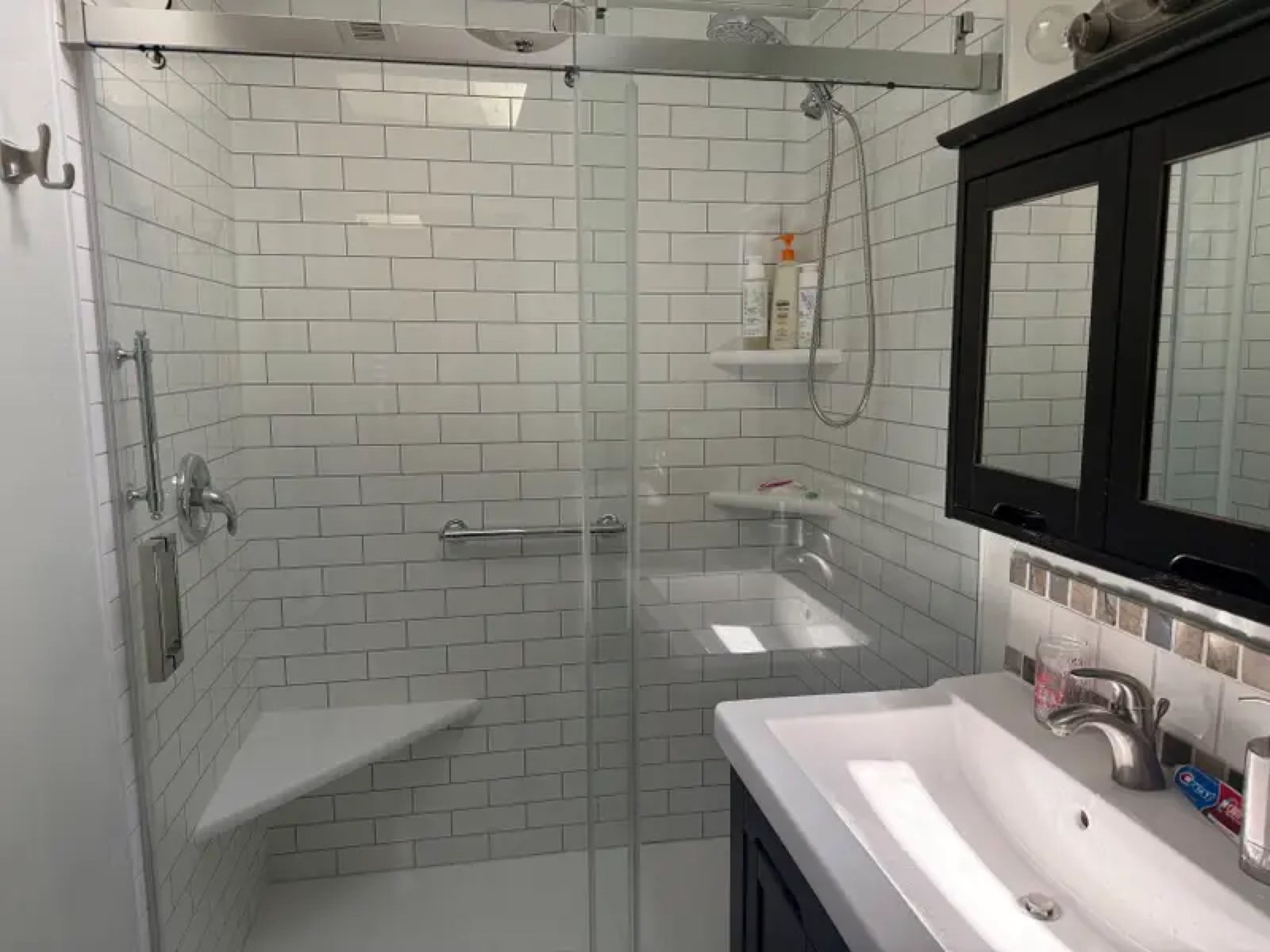White subway tile shower with glass door and dark vanity cabinet
