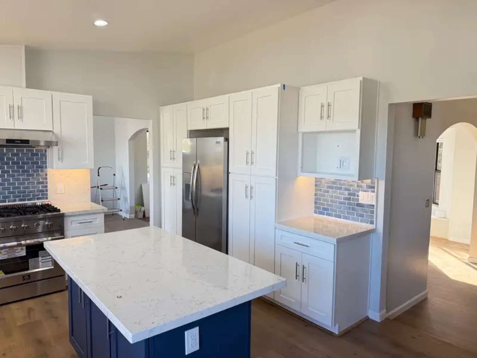 White kitchen with navy island, quartz countertop and blue subway tile